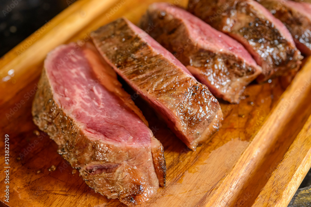 Barbecue of roasted and sliced meat on wooden board with blurred background. Barbecue of roasted and sliced meat on wooden board with blurred background.