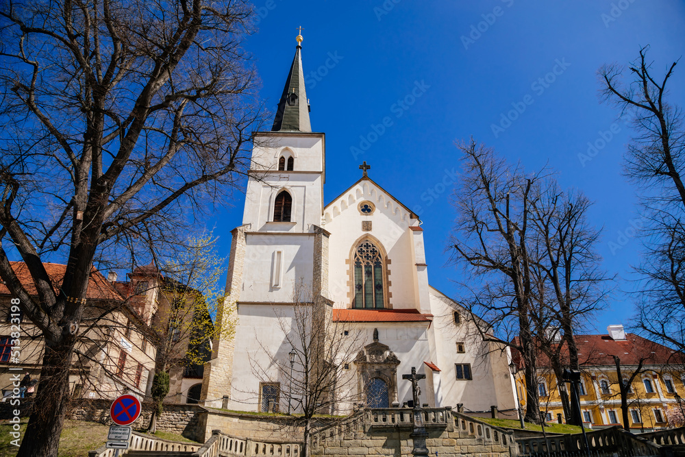 Litomysl, Czech Republic, 17 April 2022: gothic medieval church of the Exaltation of the Holy Cross with tower at sunny summer day, Chapel of St. Marquette, stone statues
