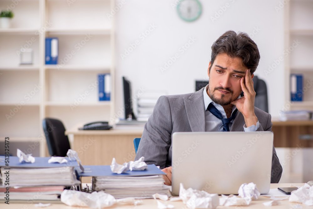 Young male employee and too much work in the office Young male employee and too much work in the office