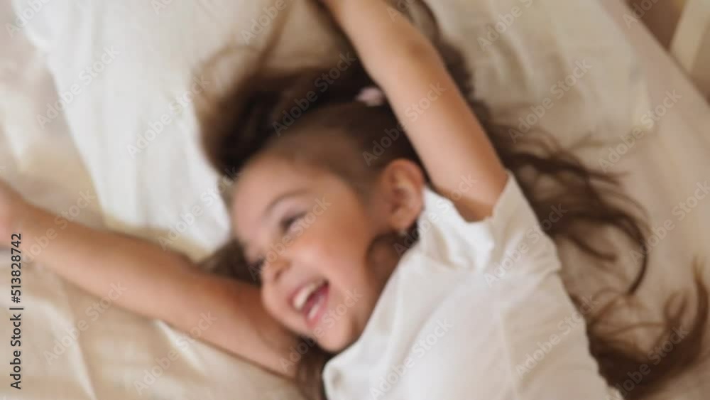 Little girl with tablet and headphones on the bed at home. Child girl listening to music or watching cartoons, chatting with friends or family before bed Little girl with tablet and headphones on the bed at home. Child girl listening to music or watching cartoons, chatting with friends or family before bed