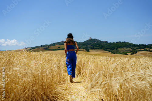 Girl walking through wheat fields in Tuscany © Julia Motinova