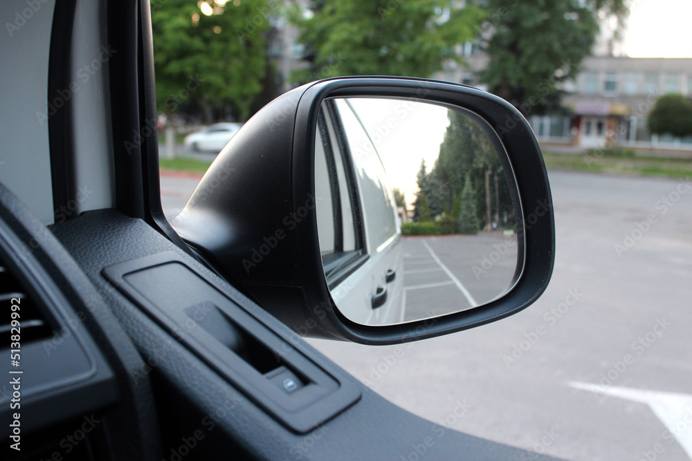 Rear-view mirror on a cargo van. Rearview mirror with reflection in it. Rear view mirror cargo van on the road. Wing mirror of a cargo van with nature street.