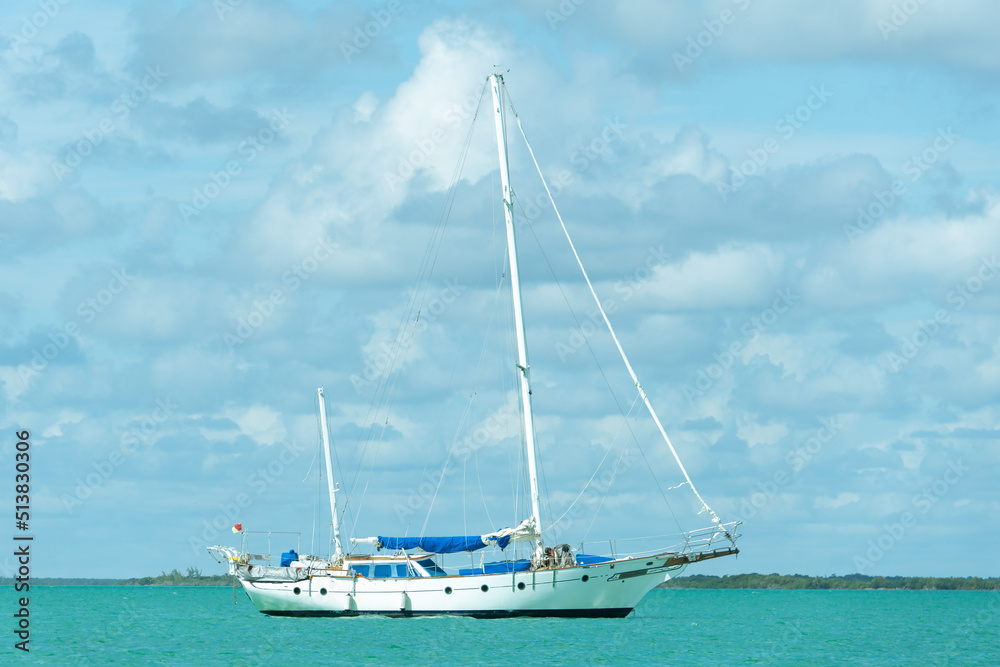 Lonely yacht with folded sail on turquoise water. Sailboat in calm. Empty boat. Lonely yacht with folded sail on turquoise water. Sailboat in calm. Empty boat.