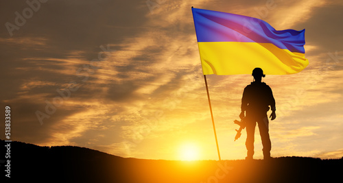 Flag of Ukraine with silhouette of soldier against the sunrise or sunset. Concept - armed forces of Ukraine. Relationship between Ukraine and Russia.