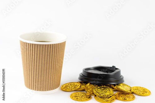 紙コップのコーヒーと、オモチャの金貨。ラテマネーのイメージ