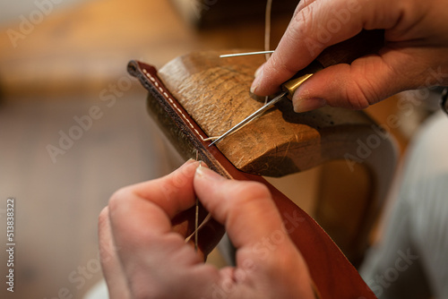 Handmade. the girl sews a leather belt in the workshop. Wooden machine. Atmospheric photo. Close up
