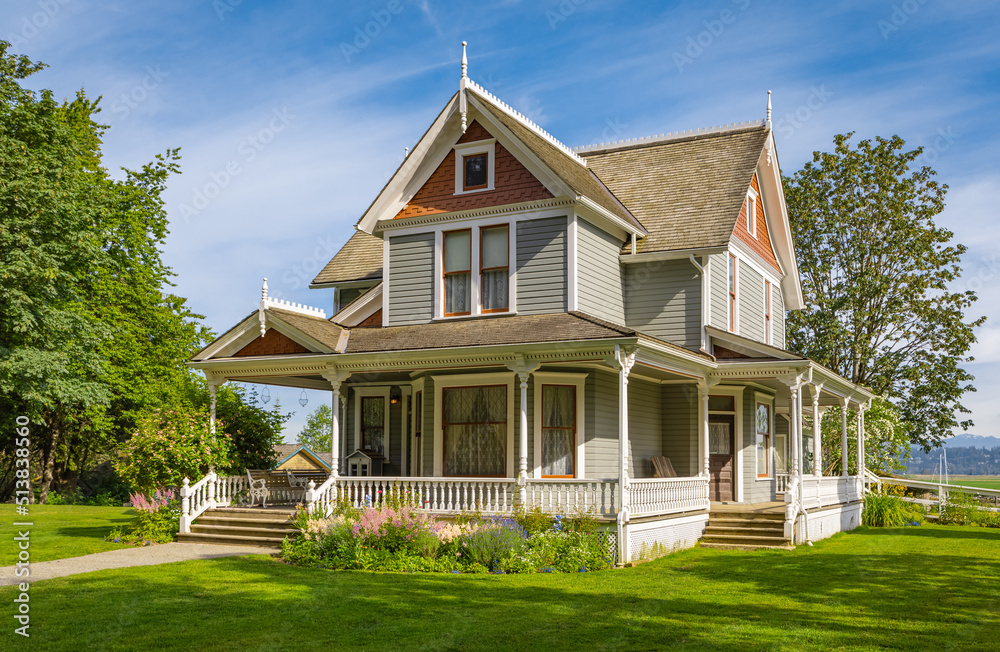 Beautiful garden design with a blossom flowerbed around house. Green lawn grass in a garden at traditional rural house Beautiful garden design with a blossom flowerbed around house. Green lawn grass in a garden at traditional rural house