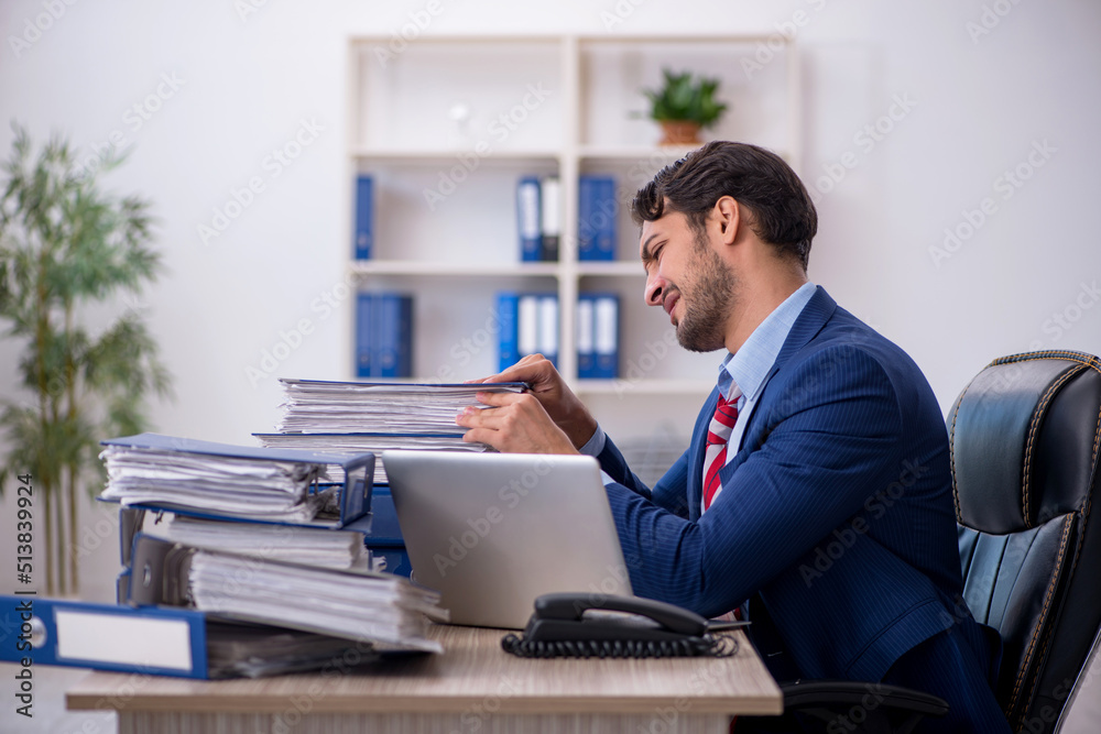 Young male employee and too much work in the office