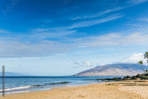 A beach in Maui Hawaii with sand  waves and a mountain in the distance