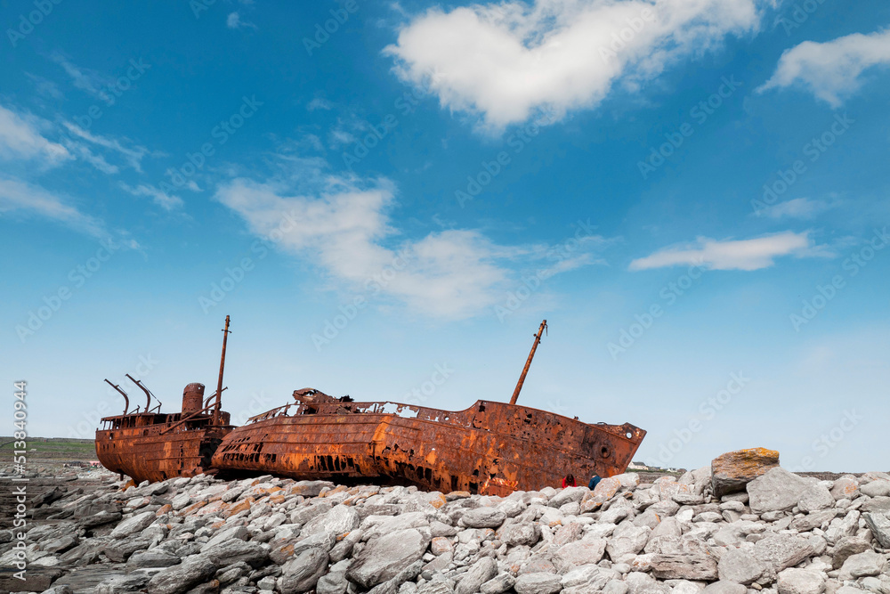 Plassey shipwreck on shore of Inisheer island. Aran islands, county Galway, Ireland. Rough stone coast and blue cloudy sky. Popular tourist landmark and attraction. Irish landscape