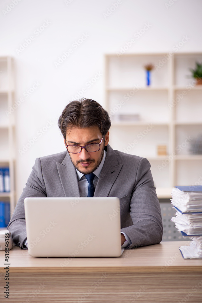 Young male employee and too much work in the office Young male employee and too much work in the office