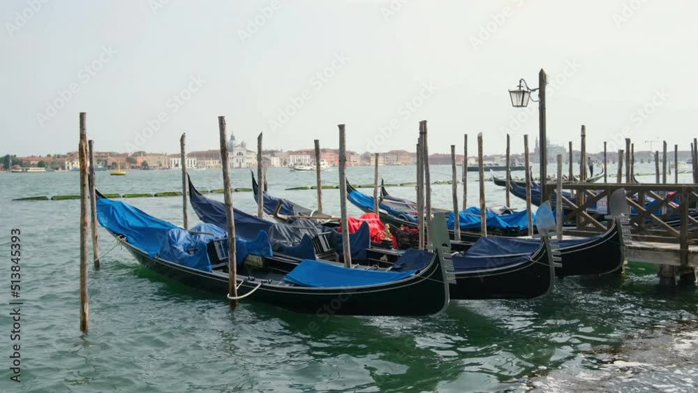 Historical gondolas parked on lagoon dock in Venice city center,Traditional water transportation,italy Historical gondolas parked on lagoon dock in Venice city center,Traditional water transportation,italy