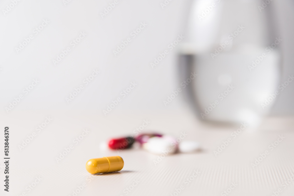 close-up of yellow pills, with pills and glass of water behind, vertical, pandemic, concept of health and wellness close-up of yellow pills, with pills and glass of water behind, vertical, pandemic, concept of health and wellness