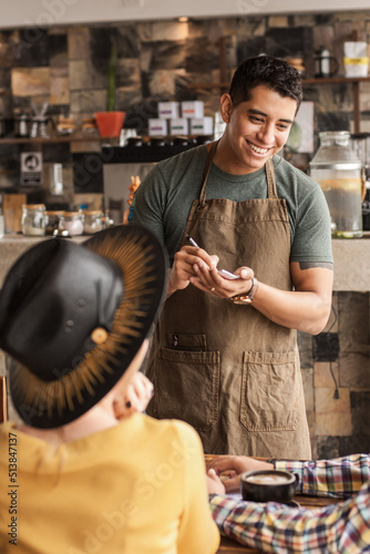 Latin American waiter taking an order in a coffee shop