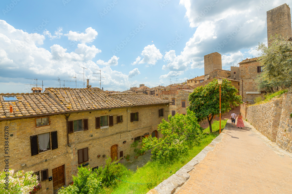 A couple walks down a path in the medieval hill town village of San Gimignano, Italy.