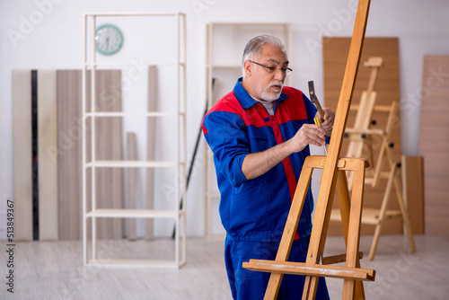 Old male carpenter repairing drawing easel