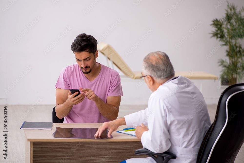 Fototapeta premium Young male patient visiting old male doctor