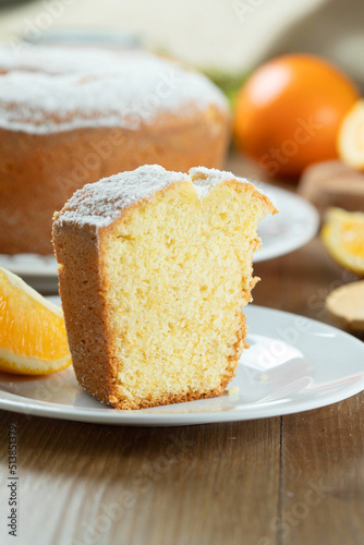 Piece of moist orange fruit cake on plate with orange slices on wooden table. Delicious breakfast, traditional English tea time. Orange cake recipe
