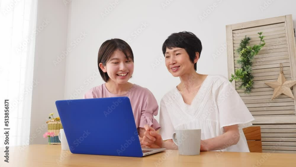 自宅でノートパソコンを見る母親と娘 自宅でノートパソコンを見る母親と娘