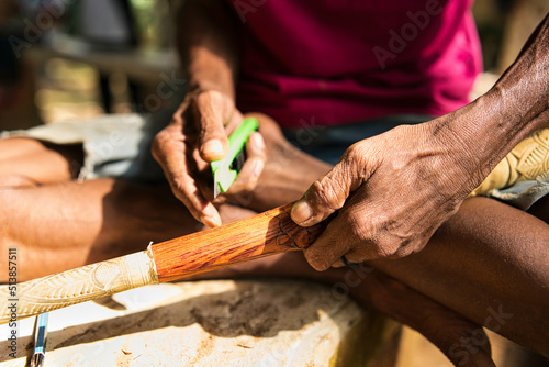 Hand of an indigenous person carving on the surface of the blowpipe or sumpit. 