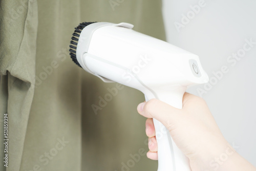 Female hand ironing a t-shirt with a portable steamer close-up.