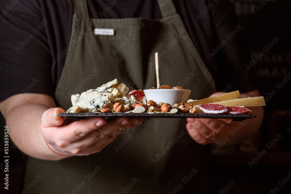 Waitress holding black stone board with delicacies.