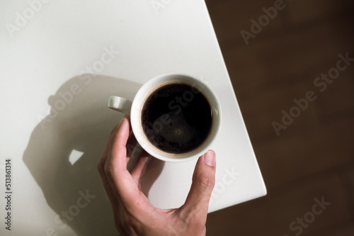 male hand holds a takeout coffee cup with an americano and top view.