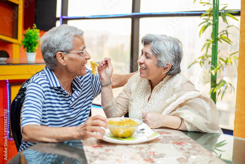 Happy indian senior couple enjoying meal together at home, asian Retired old husband and wife eating noodles, spend time. retirement life. love and care.