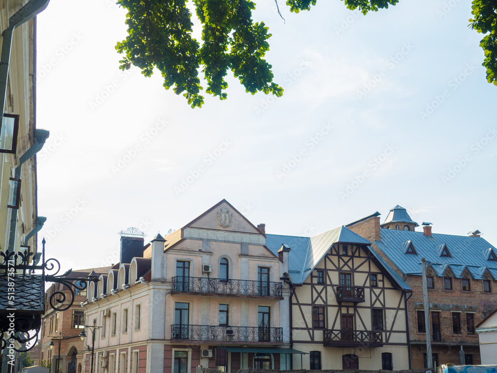 Naklejka premium Lutsk, Ukraine. Beautiful old buildings on the Drahomanov Street of Lutsk. Crowded street construction in summer evening.