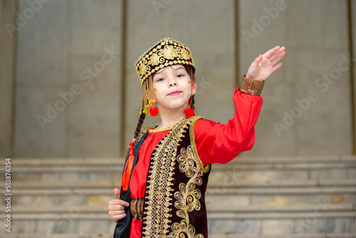 A little girl in Uzbek national costume is dancing.