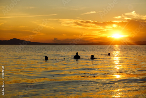 People enjoying a swim in the sea at sunset