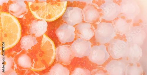 Lemon slices and orange salmon caviar with ice cubes. Panoramic banner for design on the theme of fresh seafood in gentle tones of color. top view