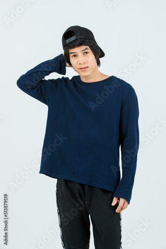 Portrait isolated cutout studio shot Asian young handsome slim teenager fashion male model in long sleeve shirt standing posing smiling holding hand adjusting black baseball cap on white background
