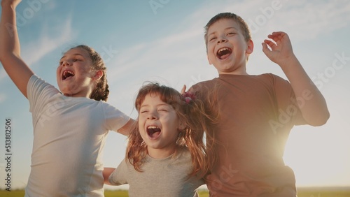 group of kids team hugging a jumping and rejoicing outdoors. happy family teamwork kid dream sun concept. family children sisters brothers have fun hugging in the park in nature © ibragimova