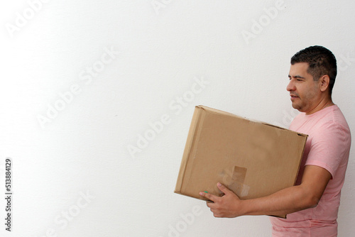 Latin adult man carries a cardboard box on the stairs of his house during a move opens house that he bought in real estate very happy for the change 