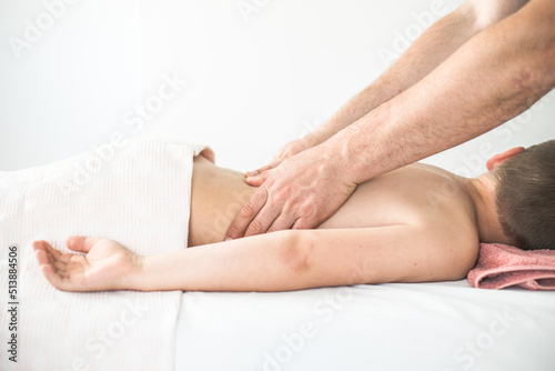 Boy toddler relaxes from a therapeutic massage. Physiotherapist working with patient in clinic to treat the back of a child