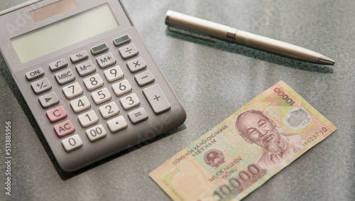Vietna money, calculator and a pen on the desk. photo