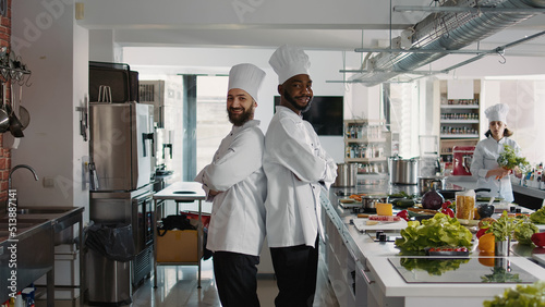 Portrait of multiethnic team of cooks working in restaurant cuisine, preparing gourmet meal with delicious fresh ingredients. Professional male chefs cooking authentic culinary food recipe.