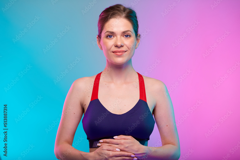 Smiling sporty woman with hand on stomach. Female fitness portrait isolated on neon multicolor background.