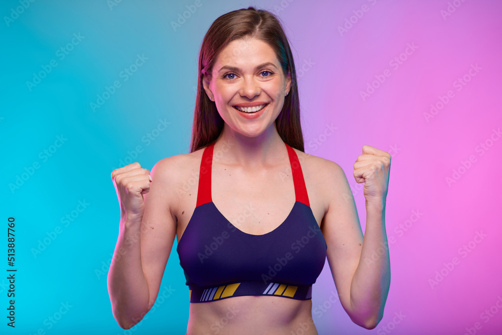 Smiling sporty woman in fitness sportswear flexes arms and demonstrates muscles. Female fitness portrait isolated on neon multicolor background. Smiling sporty woman in fitness sportswear flexes arms and demonstrates muscles. Female fitness portrait isolated on neon multicolor background.
