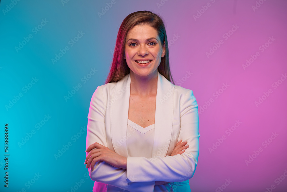Smiling business woman standing with arms crossed, portrait with neon lights colors effect. Female model on neon colored background wearing white suit. Smiling business woman standing with arms crossed, portrait with neon lights colors effect. Female model on neon colored background wearing white suit.