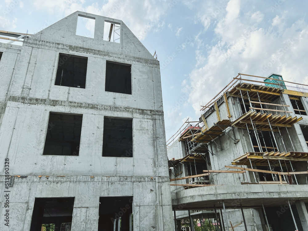 Low angle shot of a construction site with half-build structure. Process of building concrete apartment house. Concept of investing and mortgaging in the stage of home building Low angle shot of a construction site with half-build structure. Process of building concrete apartment house. Concept of investing and mortgaging in the stage of home building