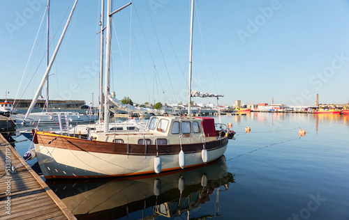 Elegant sailing boat (motorsailer) moored to a pier in a yacht marina. Transportation, pleasure craft, recreation, sport, leisure activity themes photo