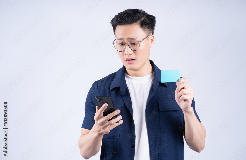 Image of young Asian man holding bank card on white background Image of young Asian man holding bank card on white background
