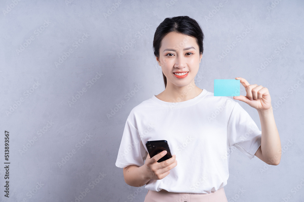 Image of young Asian woman holding bank card on background Image of young Asian woman holding bank card on background