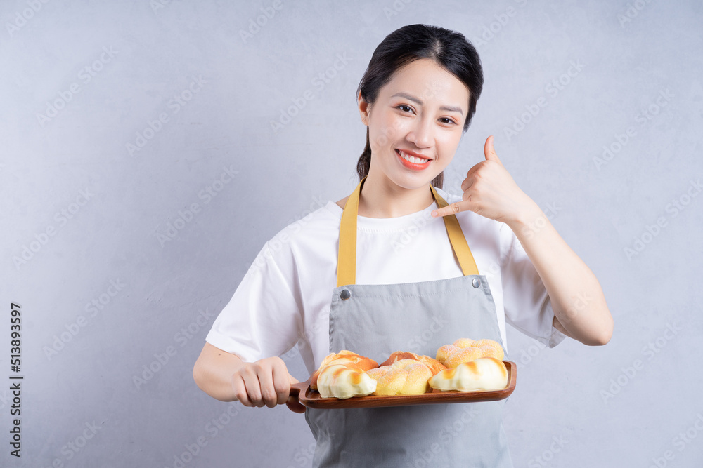Young Asian woman holding bread on background Young Asian woman holding bread on background