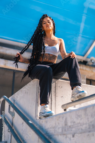 Young woman of black ethnicity with long braids and with tattoos, in the city, Urban session