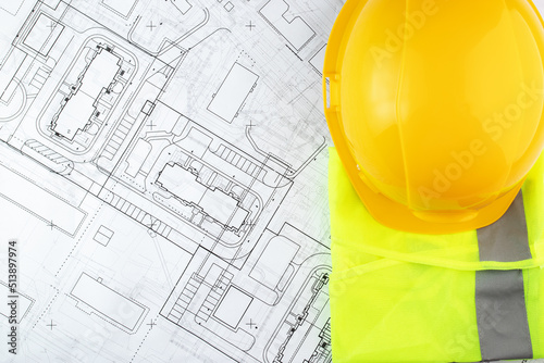 architecture, design and construction, urban development, builder's hard hat and safety vest on architectural drawings