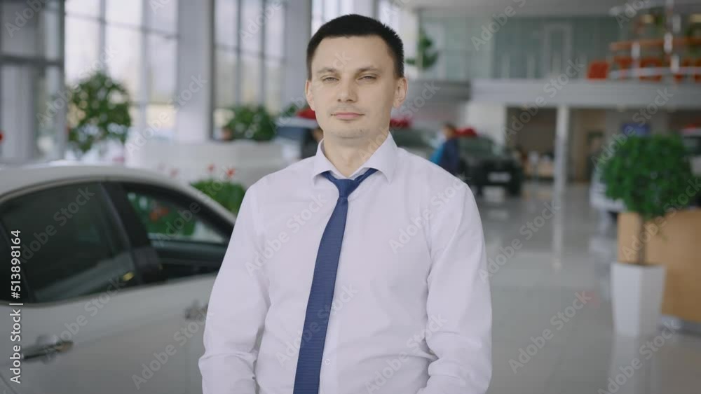 Portrait of a successful new car salesman. A man in a large car dealership. Portrait of a successful new car salesman. A man in a large car dealership.