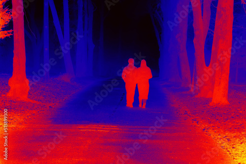 People in night park. Mystical atmosphere of night in forest. Illustration of thermal image. Blurred unrecognizable people.